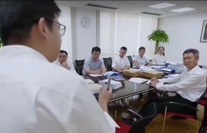 Un investigador del caso Qian conversa con un grupo en una sala de reuniones en China.